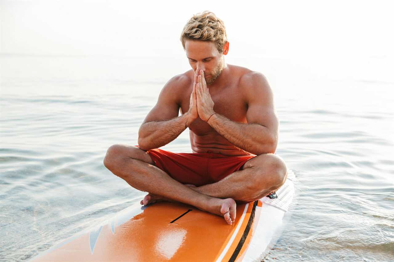 Man meditates on surfboard