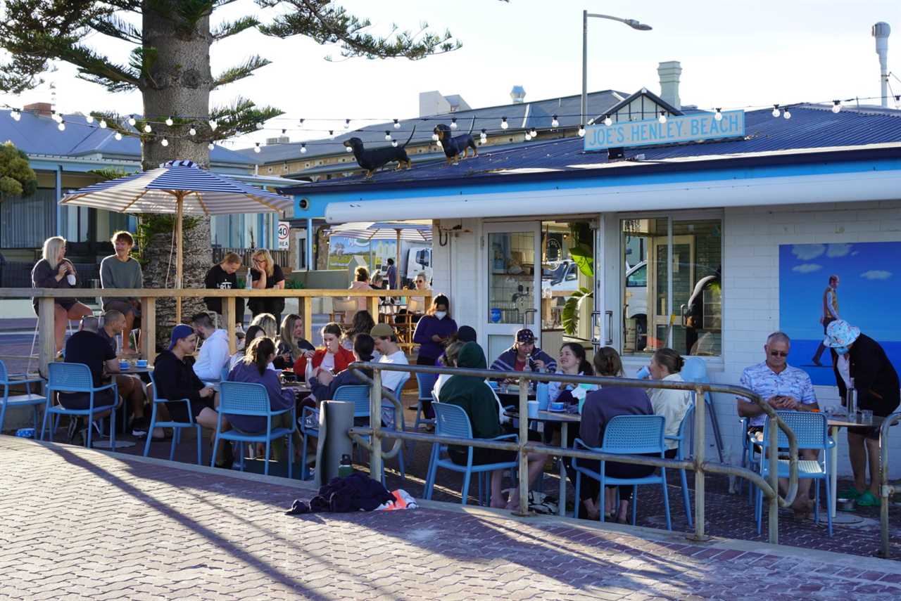 People sitting on tables and chairs outside a busy cafe