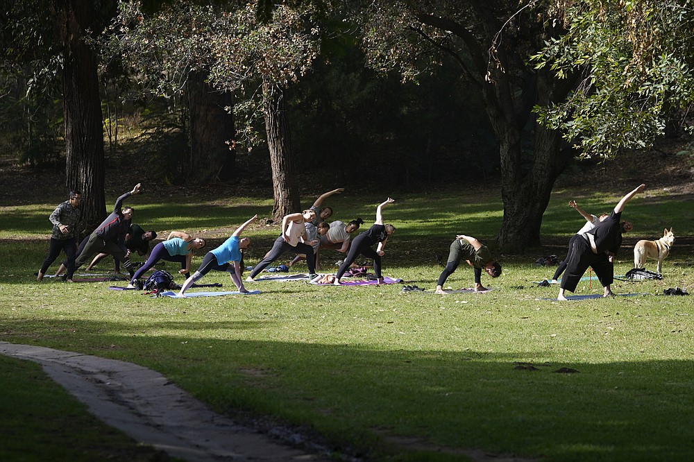 People hold an outdoors yoga class in Elysian Park Los Angeles, Saturday, Nov. 6, 2021. A vaccine mandate that is among the strictest in the country takes effect Monday, Nov. 8, in Los Angeles, requiring proof of shots for everyone entering a wide variety of businesses from restaurants to shopping malls and theaters to nail and hair salons. (AP Photo/Damian Dovarganes)