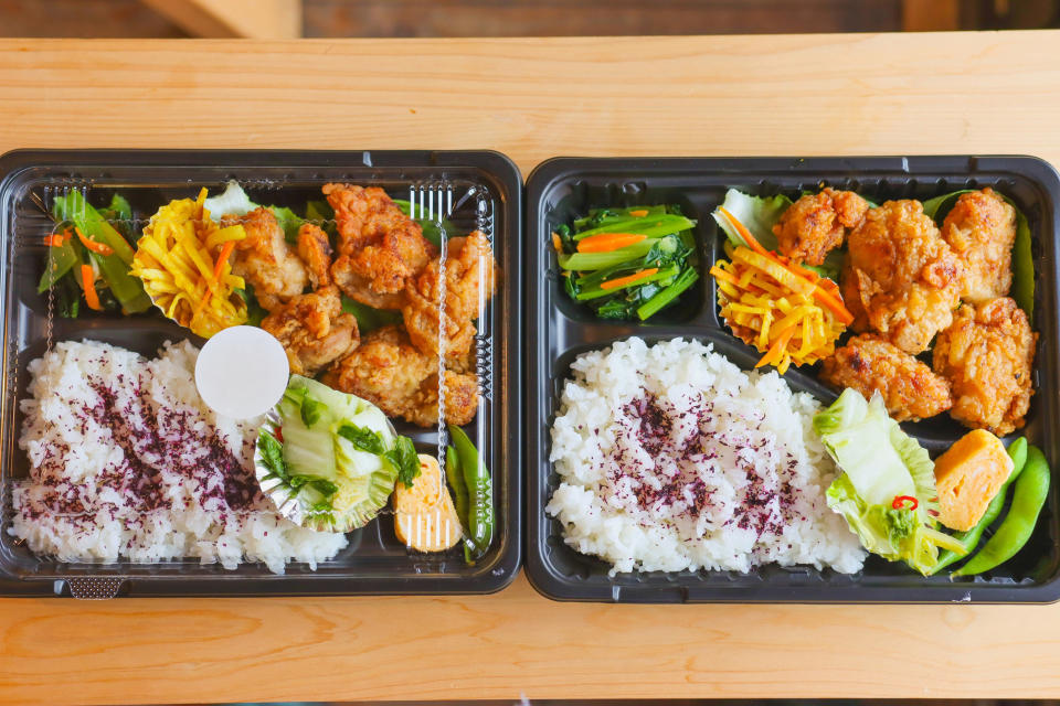 Two bento boxes with fried chicken, rice, and vegetables