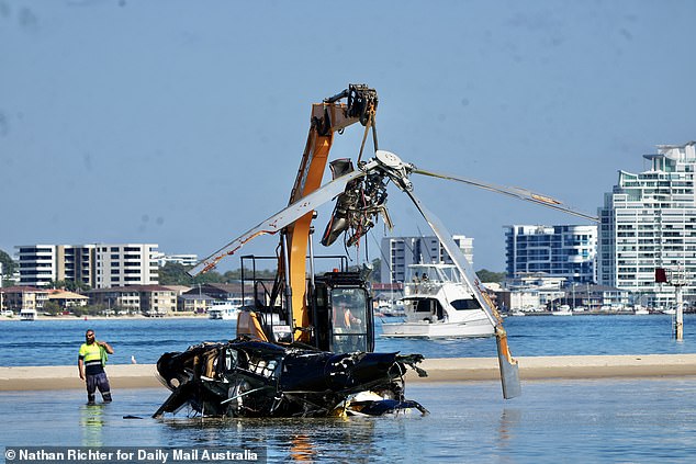 The mangled wreck of the chopper is seen on the sandbank as the detached rotor is lifted in the air